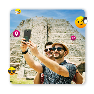 Dos hombres tomándose un selfie en las pirámides mayas en México. Ambos están rodeados de emojis.