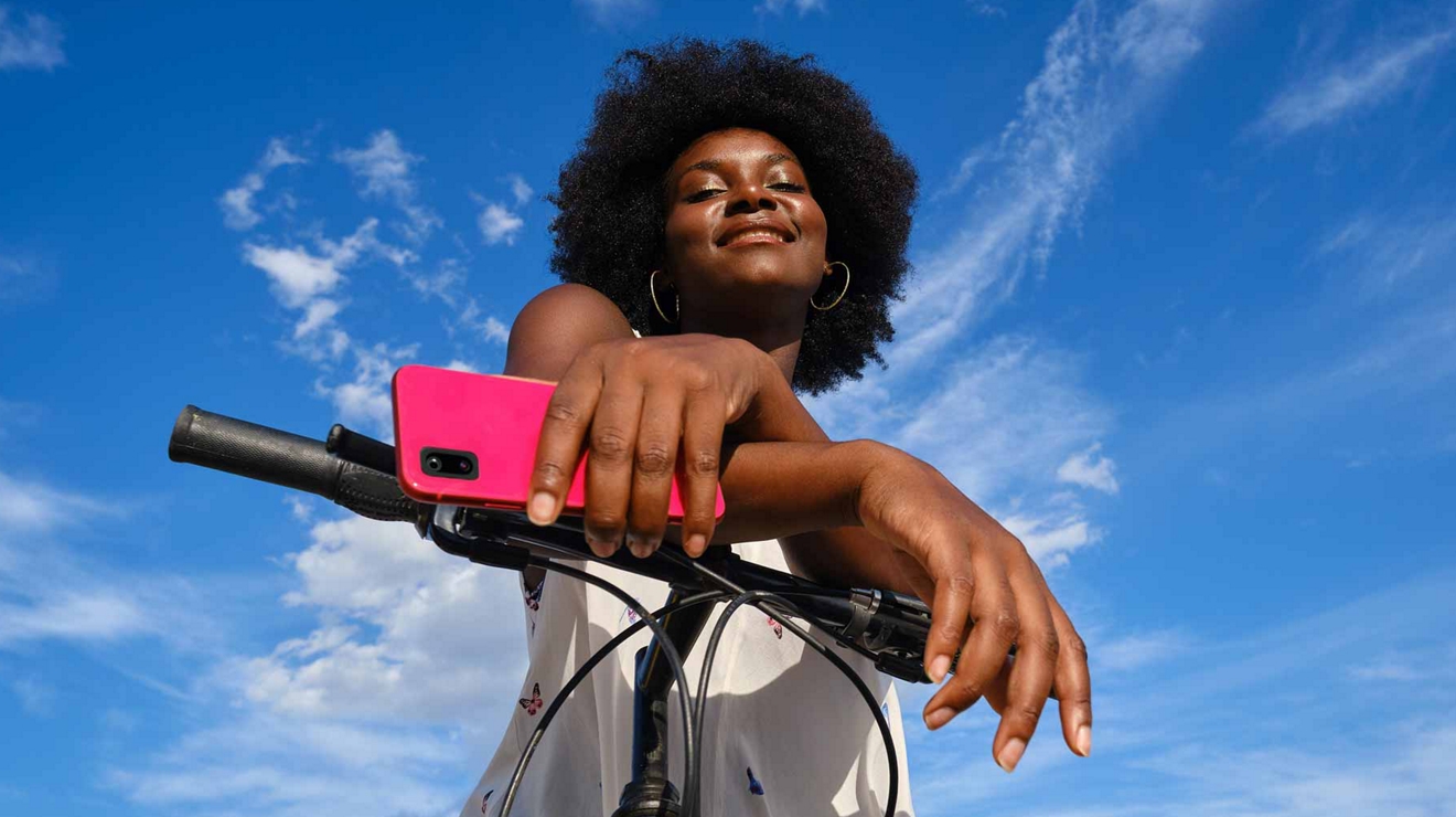 Imagen de una mujer con un teléfono en la mano montando en bicicleta