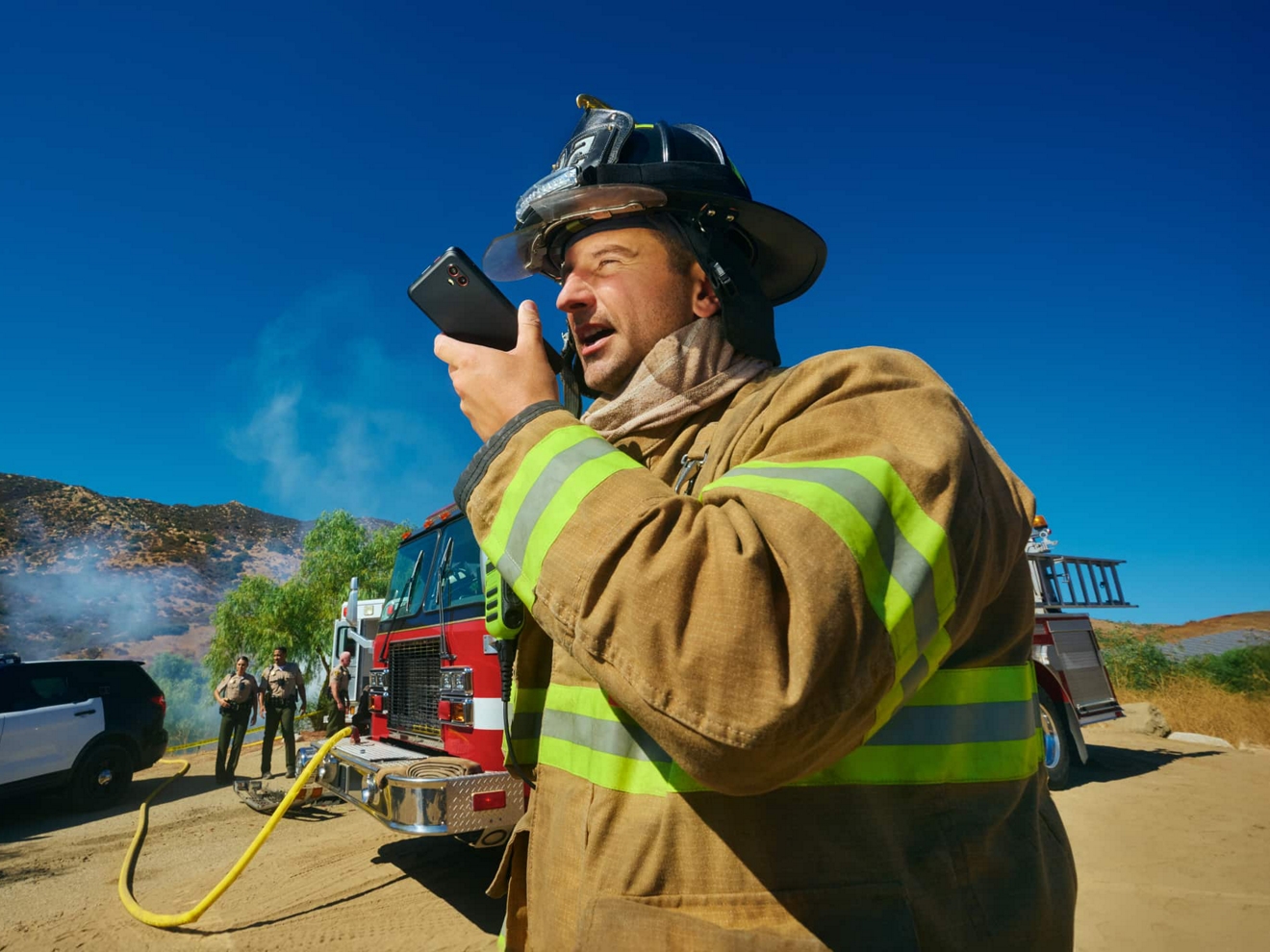 Un bombero en el lugar de una emergencia se comunica con otros miembros del equipo mediante Push to Talk.