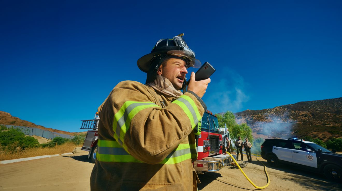 Un bombero se conecta a través de un smartphone seguro desde el lugar de un incidente en una zona rural.