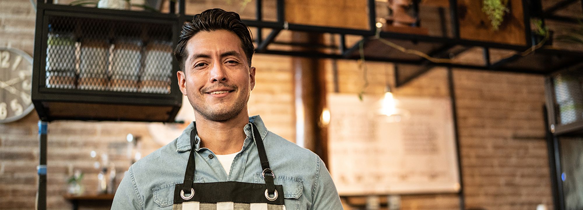 Un joven barista sonriendo con una tablet en la mano.