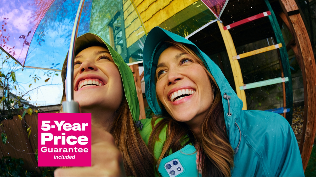 Dos jóvenes ríen y se apretujan bajo un paraguas con las palabras "precio garantizado por cinco años".