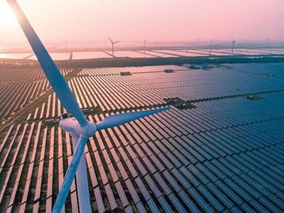 Vista aérea de parque de energía solar y eólica al atardecer.