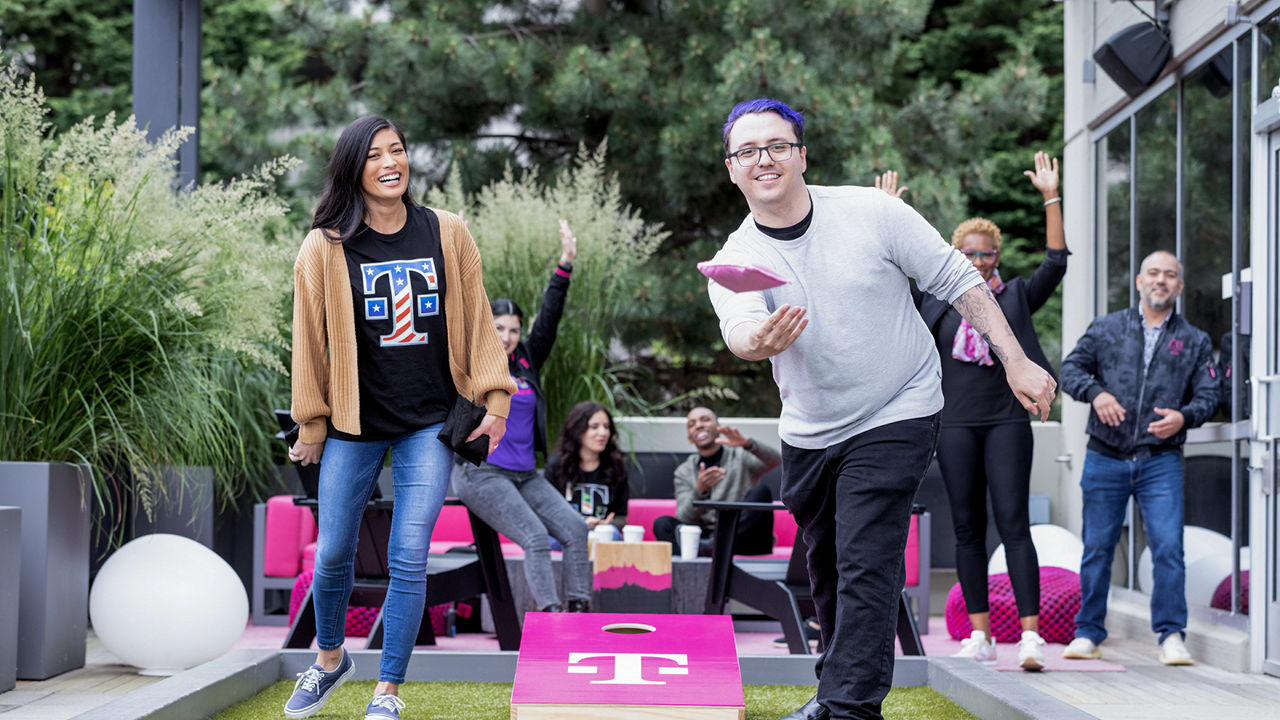 Dos empleados de T-Mobile jugando cornhole al aire libre