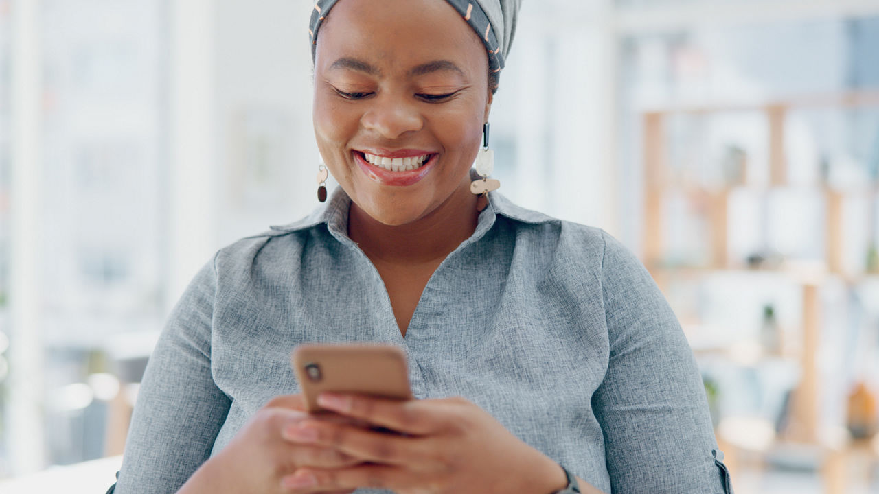 Primer plano de una persona sonriendo mientras envía un mensaje de texto en su smartphone