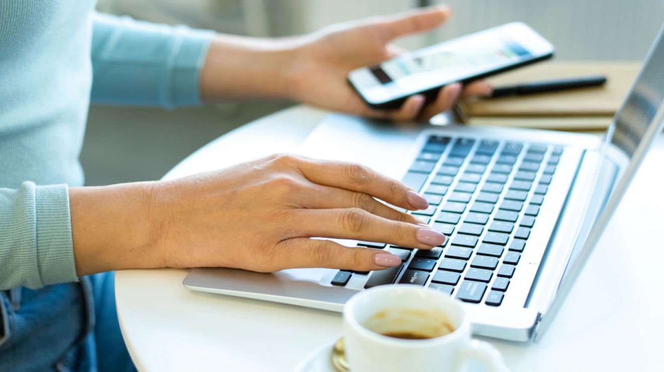 Primer plano del teclado de una laptop y un dispositivo en el fondo