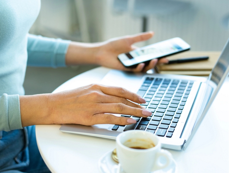 Persona trabajando en un smartphone y una laptop