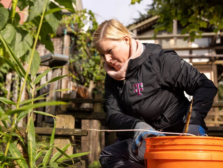Empleado de T-Mobile trabajando para ayudar a limpiar un jardín