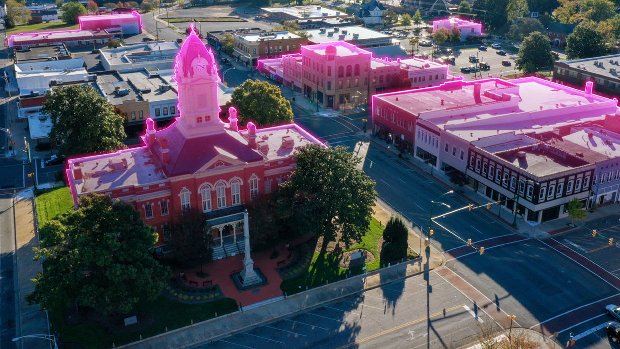 Wide shot of a small-town city hall and surrounding buildings with magenta highlights