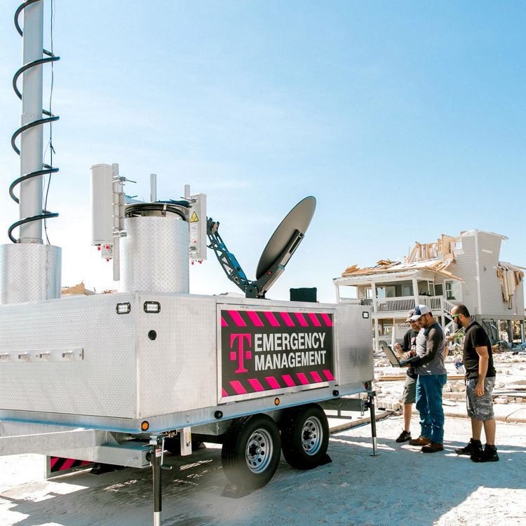 Equipo de T-Mobile reunido alrededor de una laptop junto a equipamiento de gestión de emergencias de T-Mobile