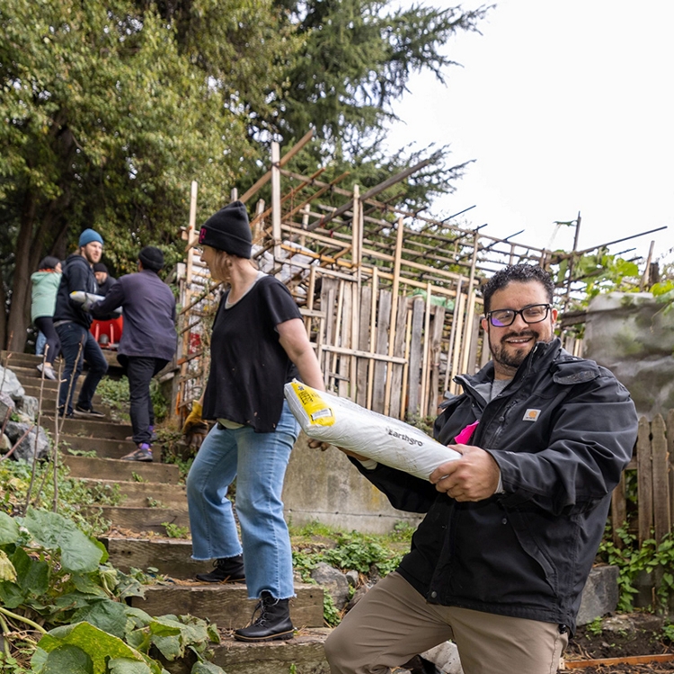 Equipo de personas forman una cadena humana en unas escaleras al aire libre para pasar unas bolsas de unos a otros