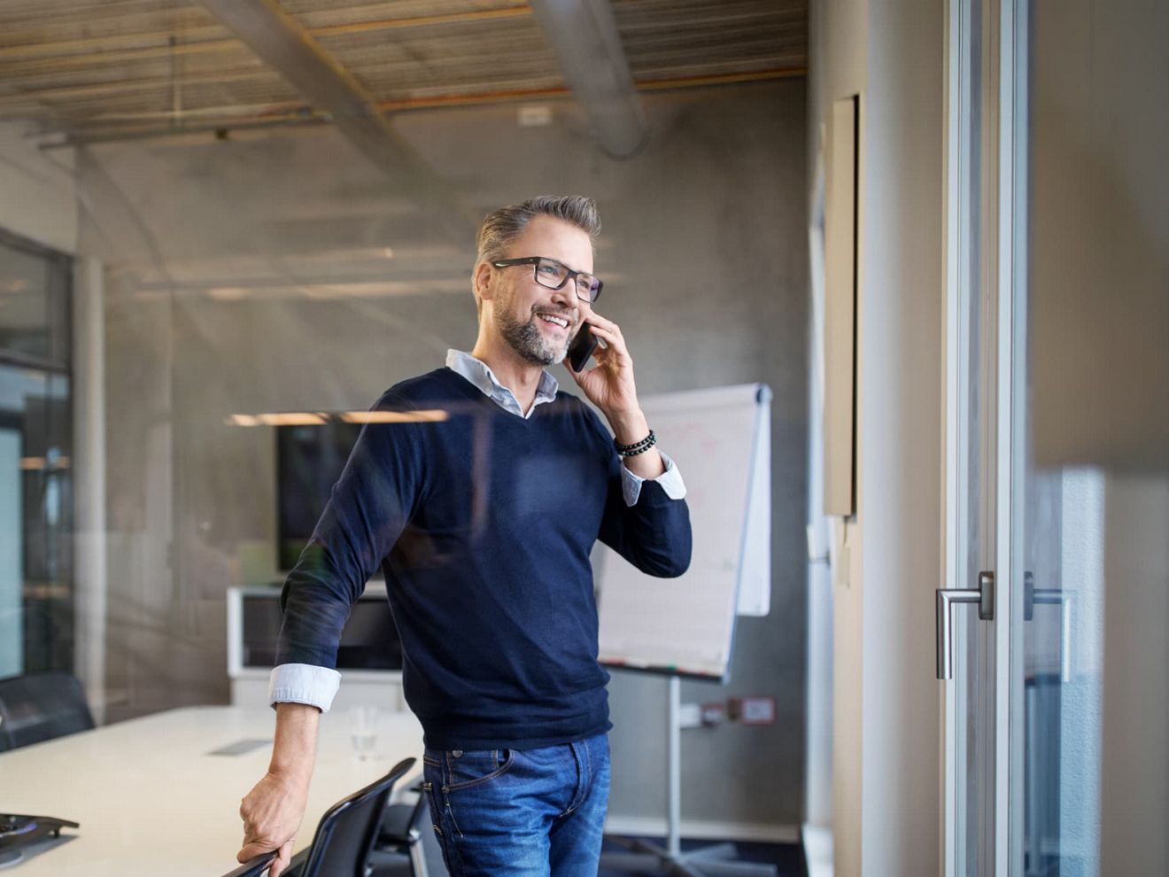 Un profesional de los negocios, en una sala de reuniones vacía, se conecta con su smartphone a través de T-Mobile MultiLine.