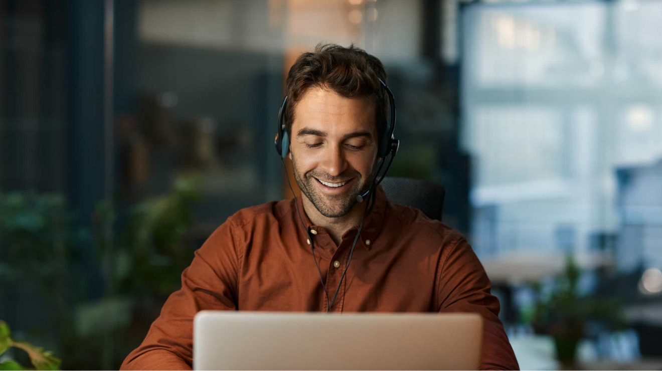 Un trabajador del gobierno usa audífonos mientras atiende una llamada de conferencia en una laptop.