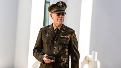 Un agente uniformado camina con un teléfono en la mano.