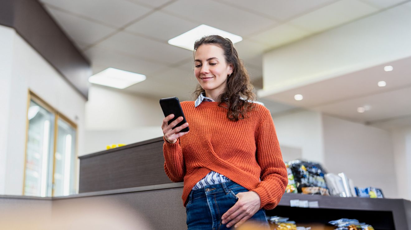 Empleada de una tienda en un descanso usando su smartphone para revisar el inventario.