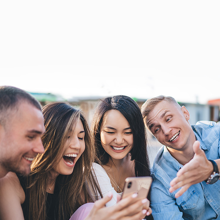Un grupo de amigos mirando un iPhone y sonriendo