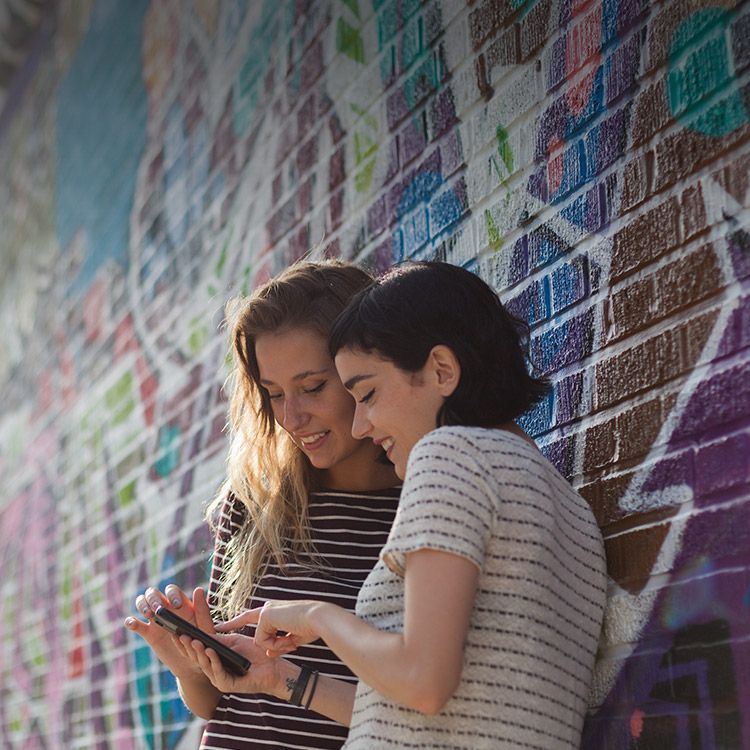 Two women smiling and looking at phone.