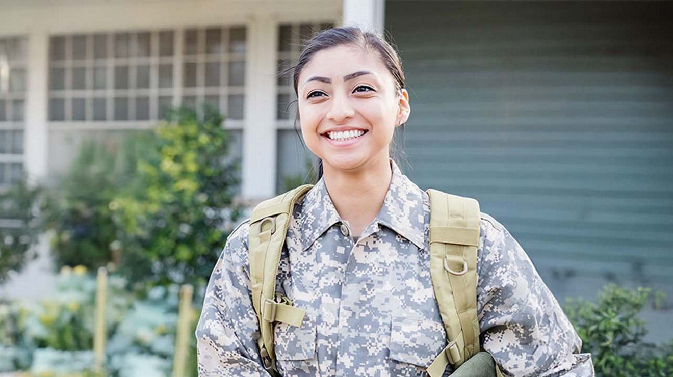 ​​​​​​​Una persona joven con uniforme militar sonríe a la cámara.