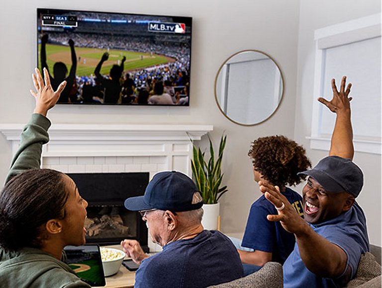 Un grupo de amigos en un sofá alentando un juego de Las grandes ligas en la televisión.
