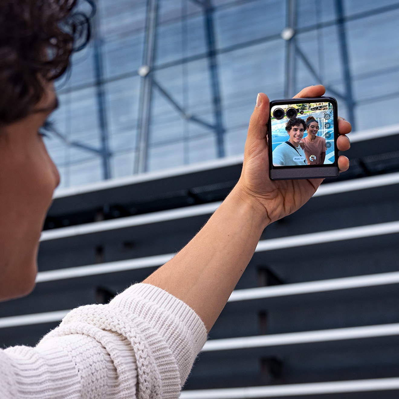 ​​Una persona sostiene su razr para tomarse una foto con un amigo con la pantalla externa del teléfono.​