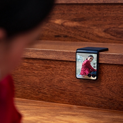 ​Una persona posa para un selfie con la pantalla externa del razr+ apoyado sobre una escalera.