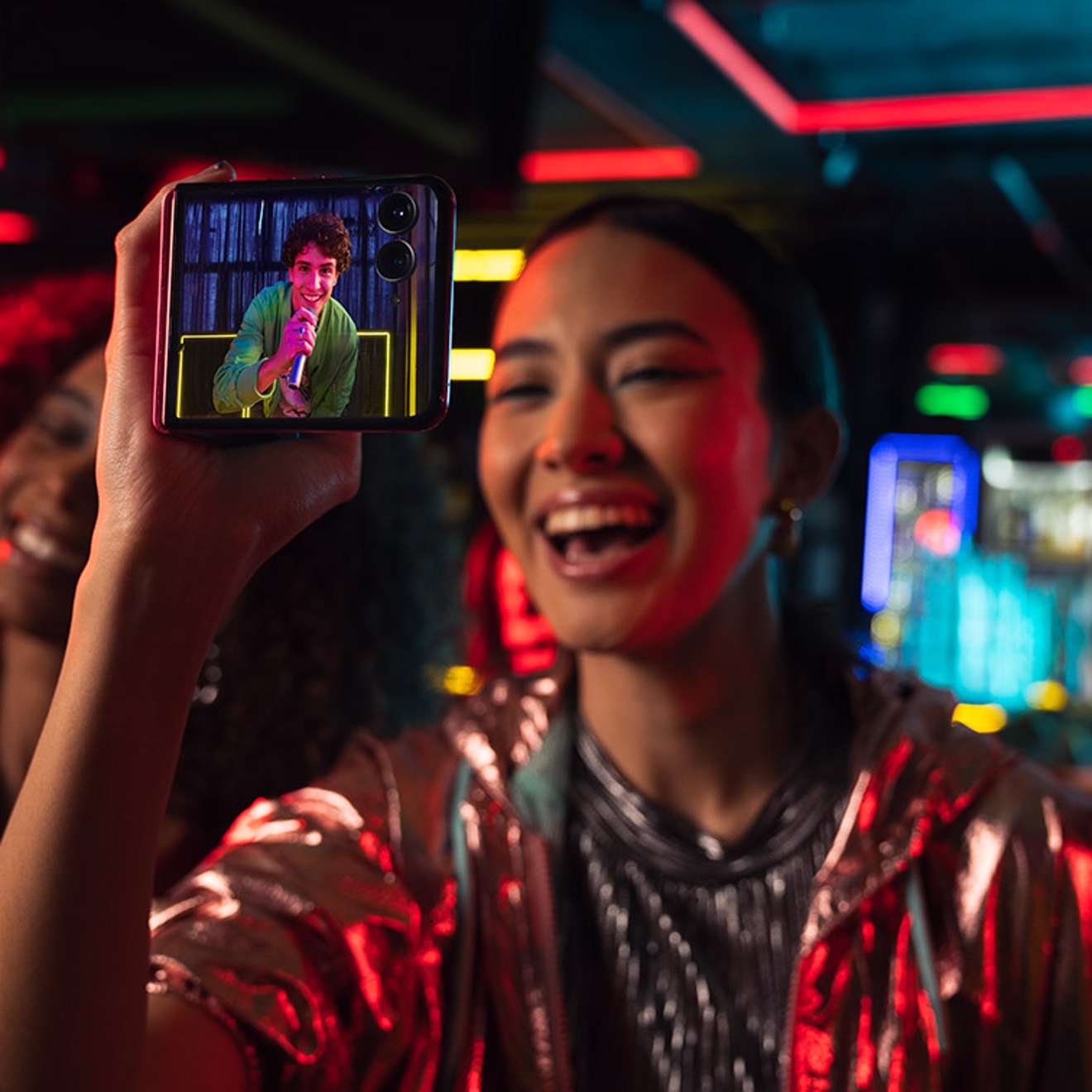 ​Una mujer sonríe mientras sostiene el razr+ con la pantalla externa mirando hacia afuera.​