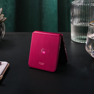 Motorola razr ultra parcialmente plegado, sobre una mesa de luz.