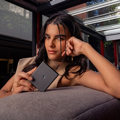 Una mujer sostiene un razr plegado mientras está sentada en un sofá, apoyando su rostro sobre la mano.