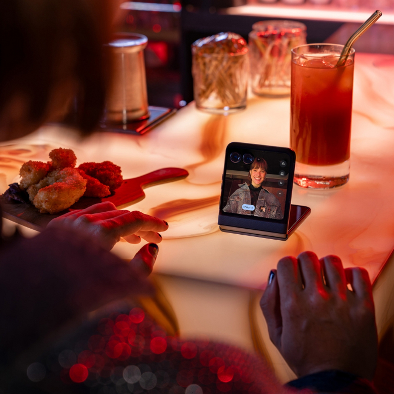 Persona en un restaurante usando un Motorola razr para chatear por video con un amigo.