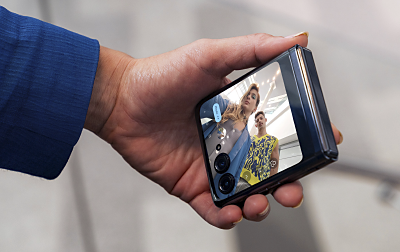 Una mano sostiene un smartphone azul y se ubica para tomar un selfie.