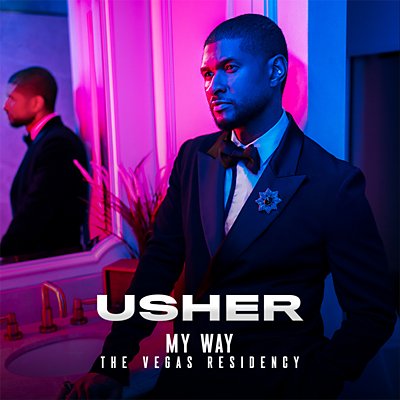 Usher de pie delante de un espejo, sombreado con luz azul y rosa.