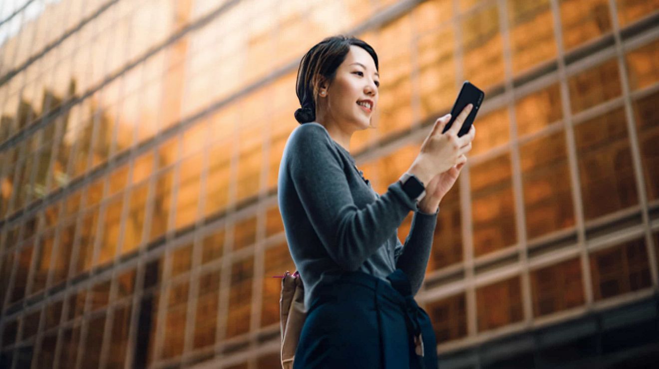 Un empresario en la calle de una ciudad envía mensajes de texto a un colega a través de su smartphone conectado con 5G de T-Mobile.
