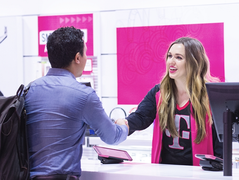 Un empleado de T-Mobile estrechándole la mano a un cliente en una tienda T-Mobile.
