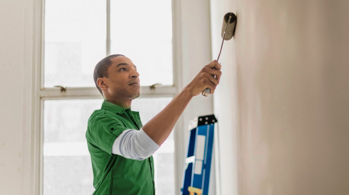 A SERVPRO professional painting an interior wall, working seamlessly from the field.