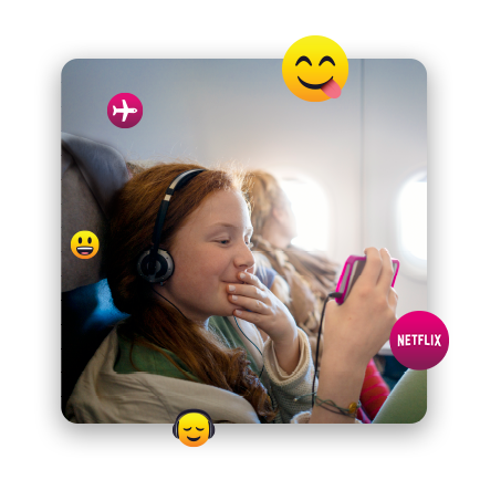 Una jovencita en un avión con auriculares puestos que mira algo en su teléfono