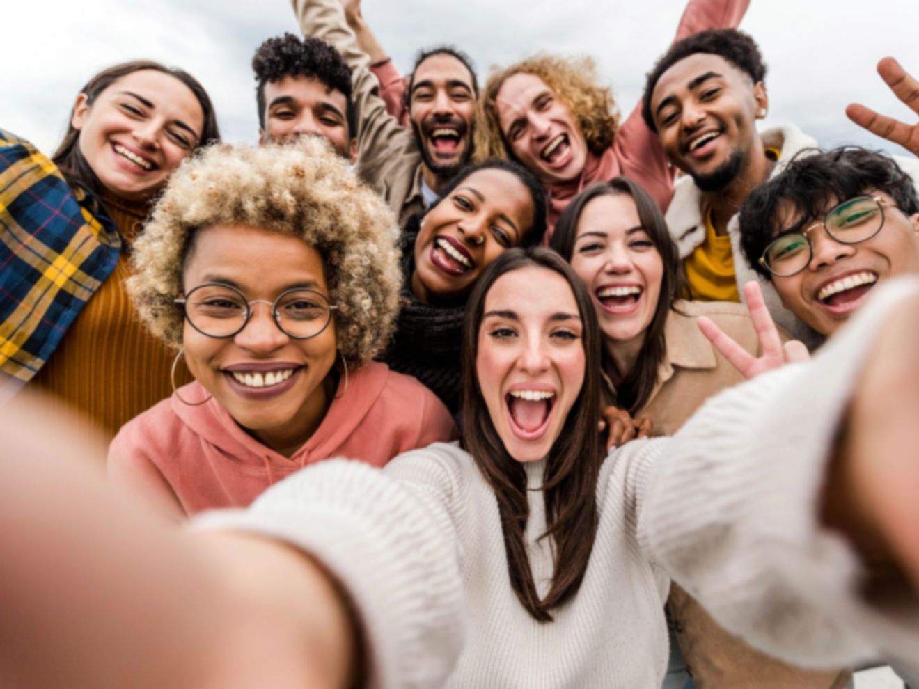 Grupo numeroso de personas tomándose un selfie con un smartphone.