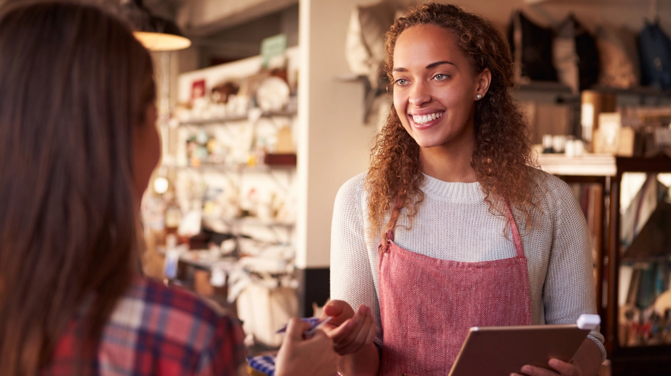 Vendedora aceptando el pago de una cliente en una tienda de un pequeño pueblo.