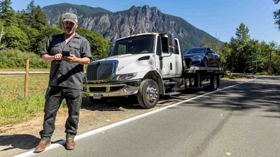 Un conductor de grúa nivela la plataforma para transportar un vehículo accidentado.