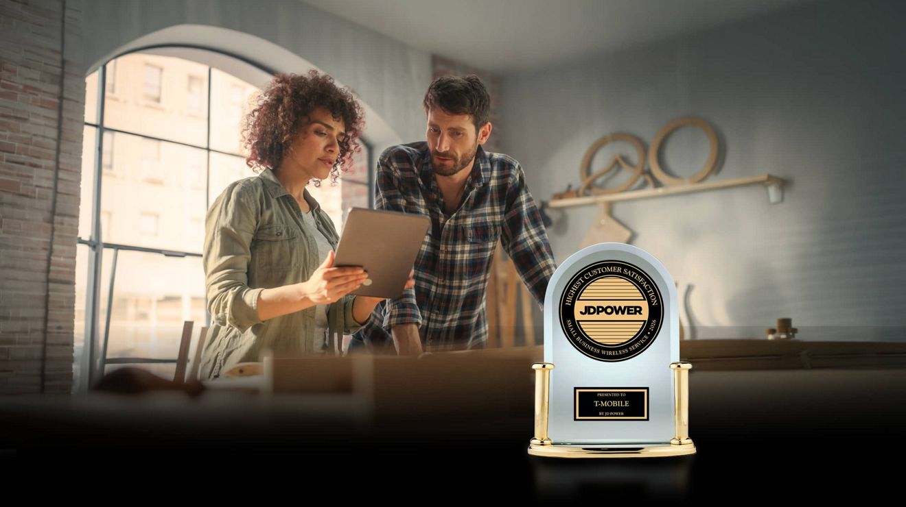 Dos propietarios de pequeños negocios revisan opciones de servicios móviles para empresas en una tablet, junto a un premio de JD Power a la satisfacción del cliente de servicios móviles para empresas.
