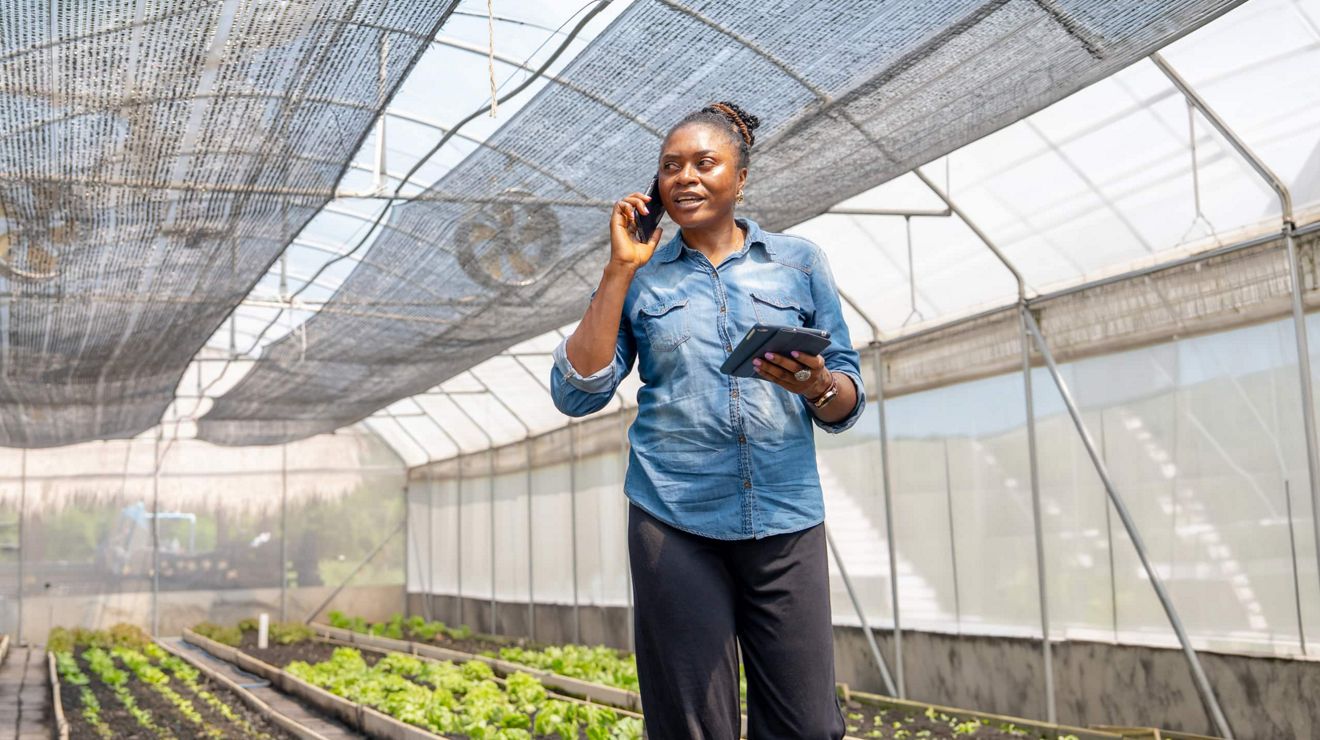 Una gerente agrícola habla por un smartphone mientras sostiene una tablet en Metrolina Greenhouse.
