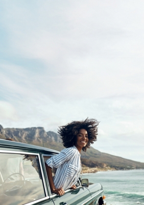 Mujer sonriendo con la cabeza fuera de un auto