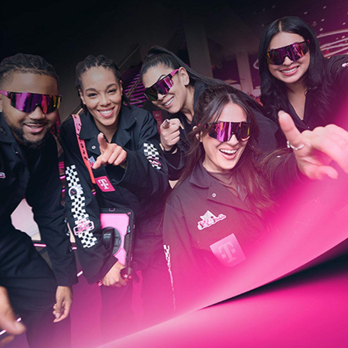 Un grupo de aficionados de F1 con ropa deportiva de T-Mobile posando con entusiasmo para un selfie.