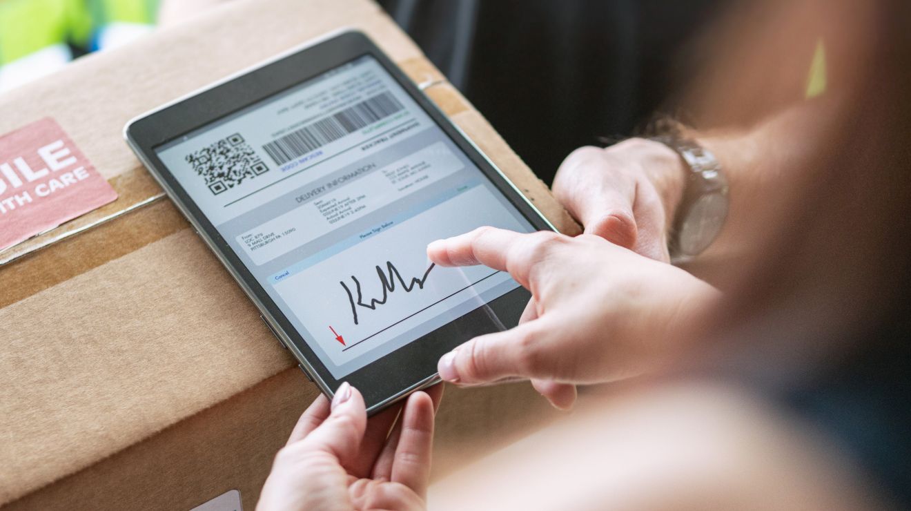 Conductor confirma la entrega con un cliente al pedirle que firme en una tablet.