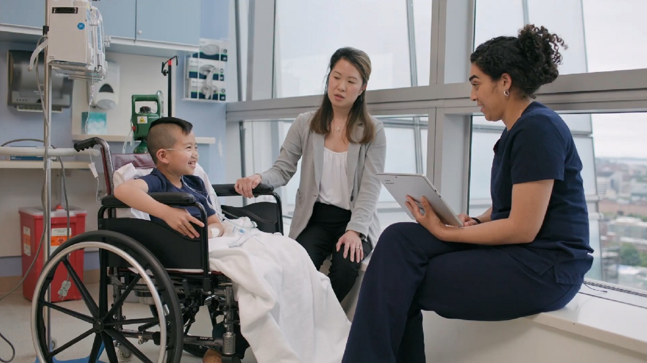Niño en silla de ruedas con su madre y una enfermera sentadas junto a él.