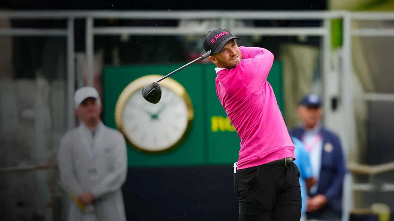 hombre vestido de magenta haciendo swing con un palo de golf