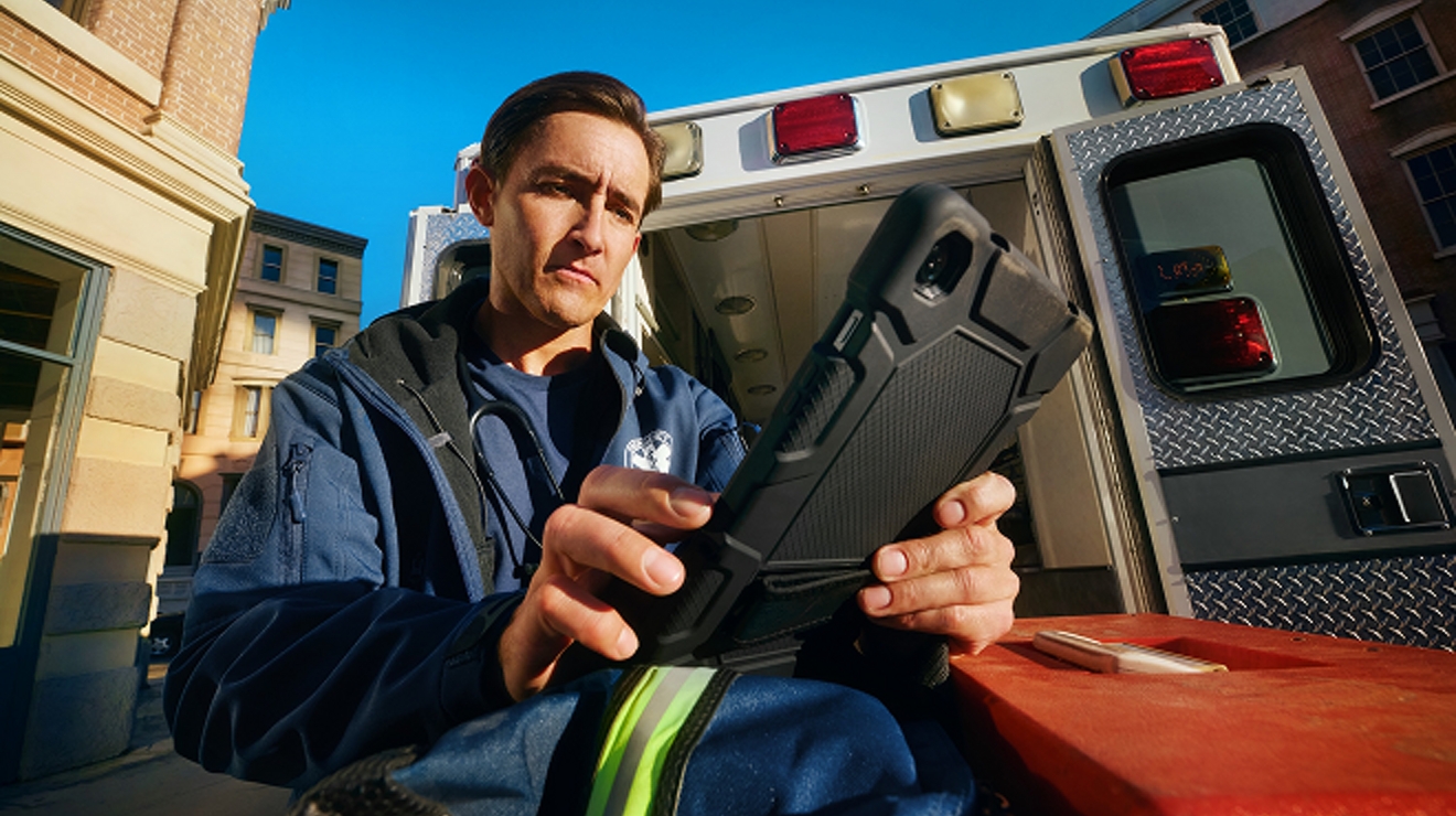 Un trabajador de torre con equipo de seguridad sube a una torre celular en una zona rural.