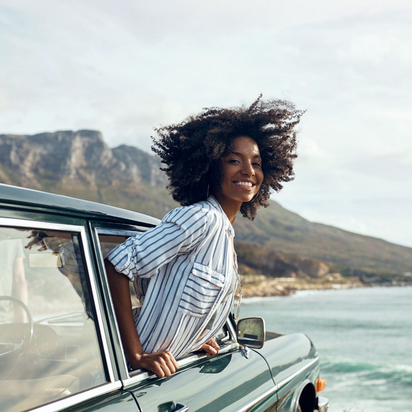Mujer sonriendo con la cabeza fuera de un auto