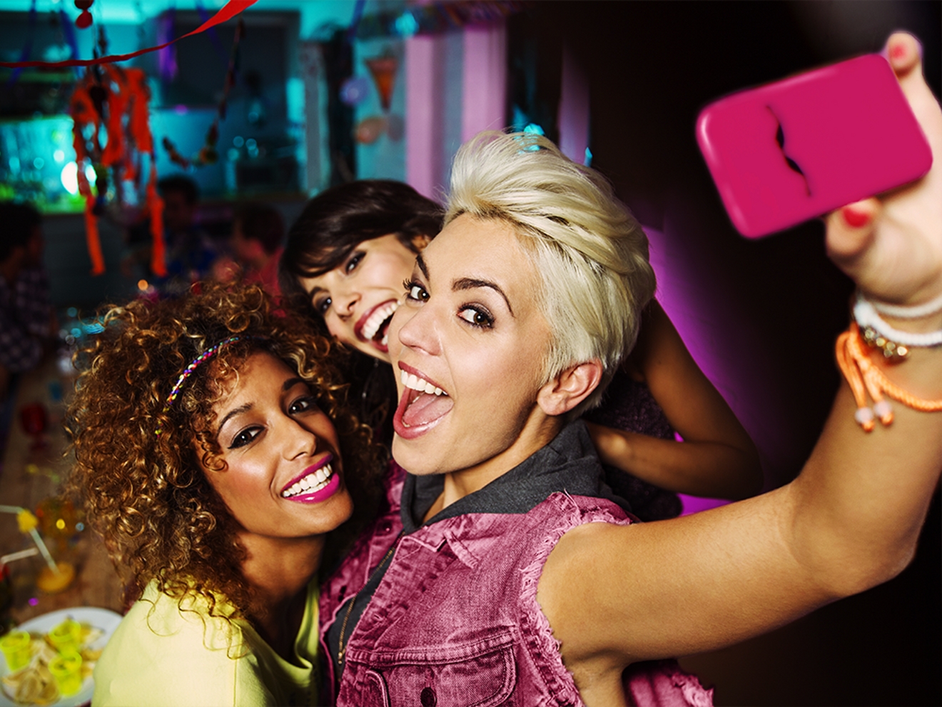 Tres mujeres sonríen mientras se toman un selfie juntas.