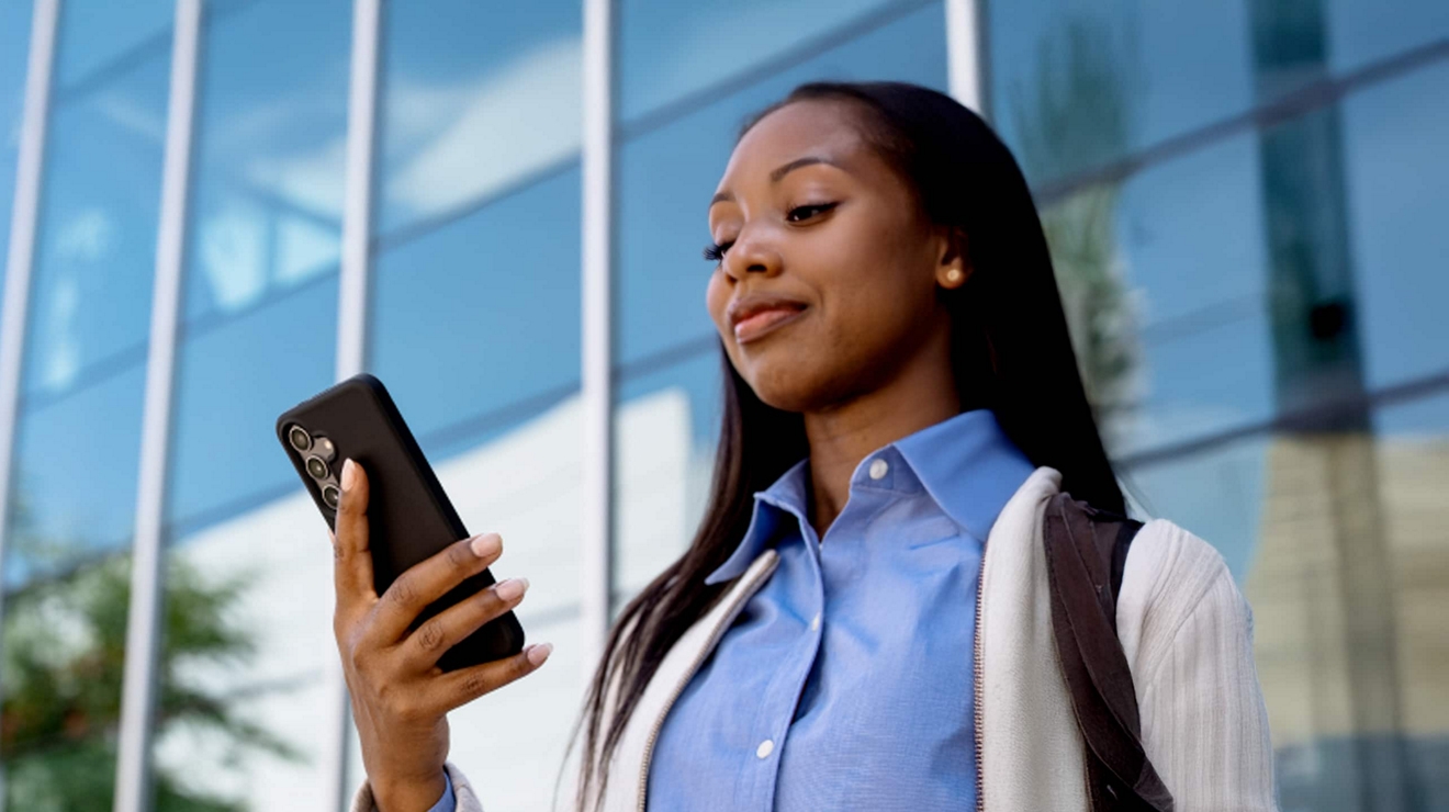 Un profesional utiliza un smartphone fuera de un edificio de oficinas.