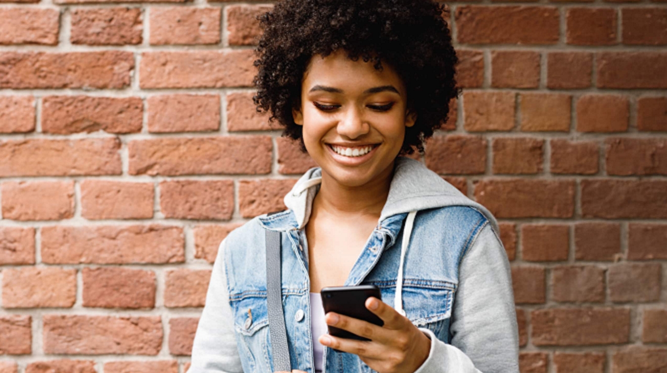 Un estudiante revisa su smartphone mientras está afuera en la escuela.